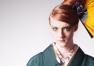 Young woman in green kimono with gold fans in her hair